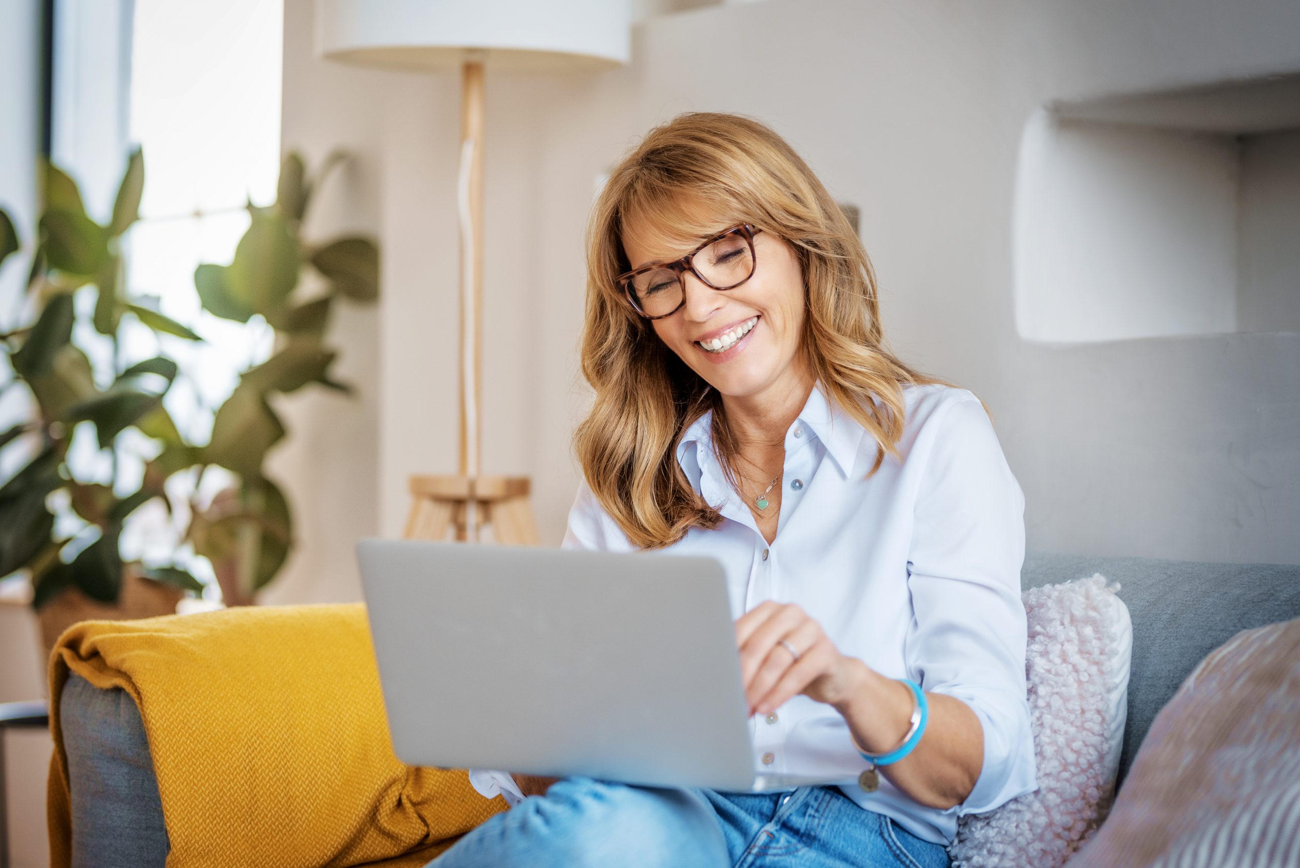 Happy woman using laptop while sitting on the couch at home