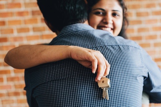 Woman hugging man while holding key - Educators Financial Group