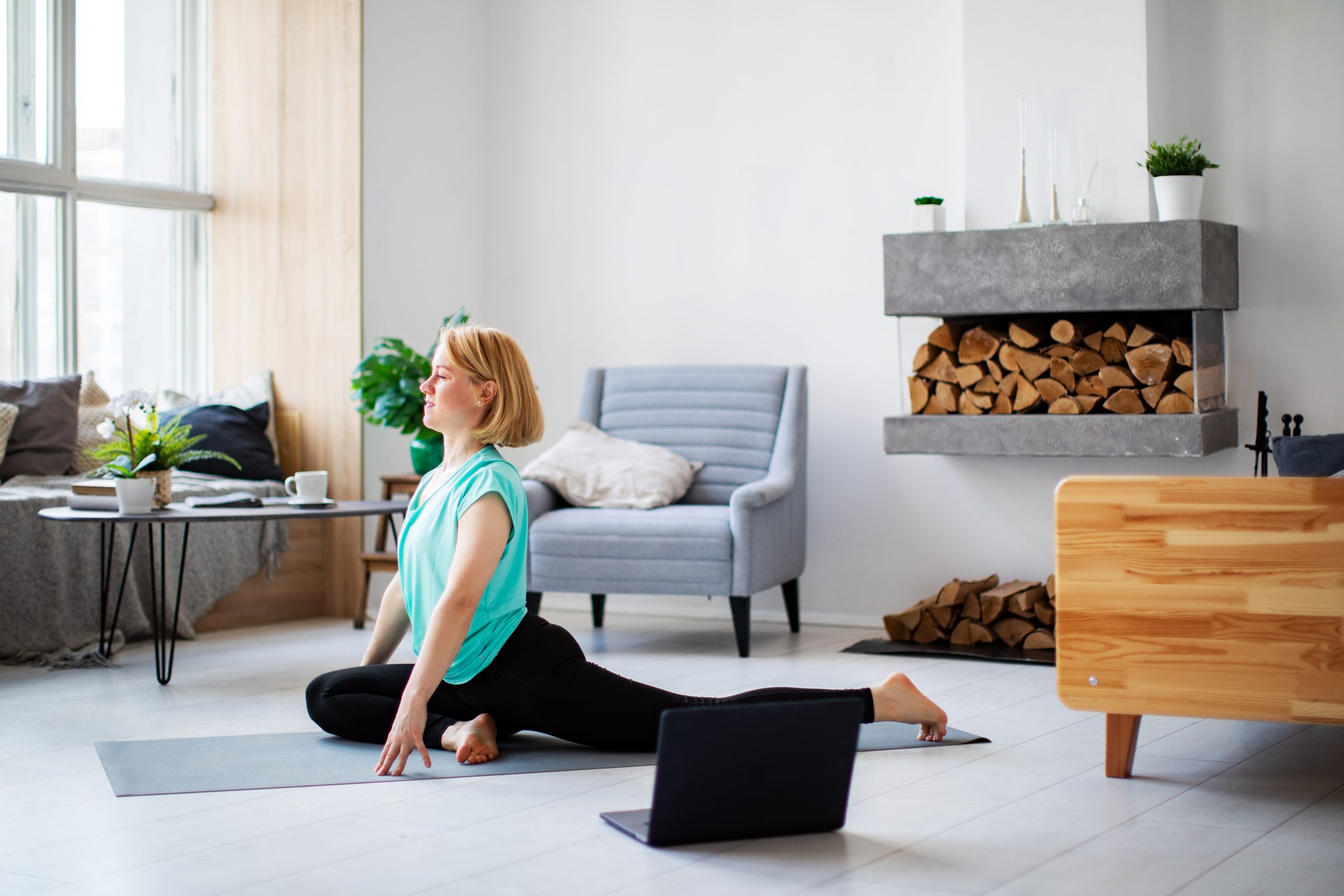 Young woman practicing yoga at home with laptop during quarantine