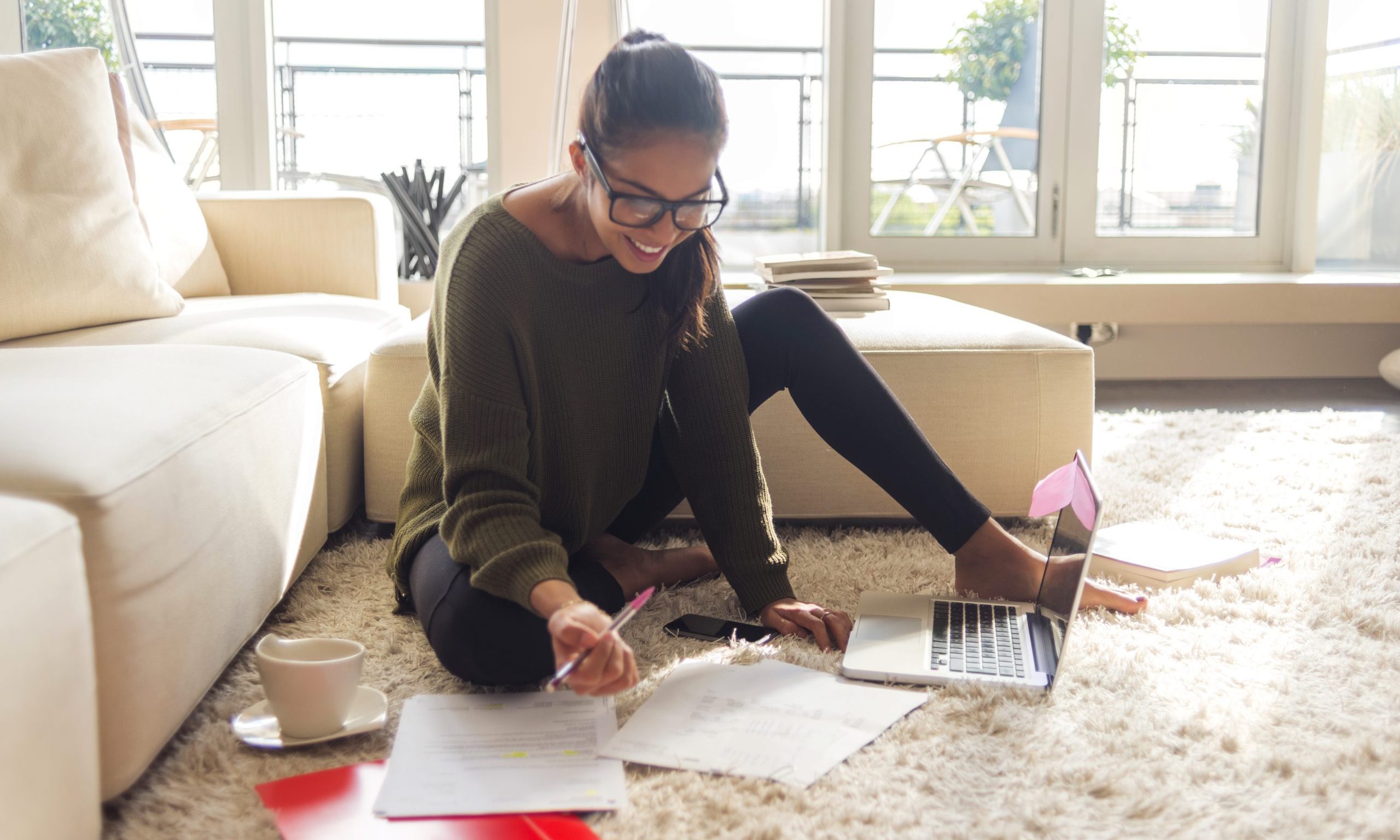 smiling young woman working on laptop in her living room