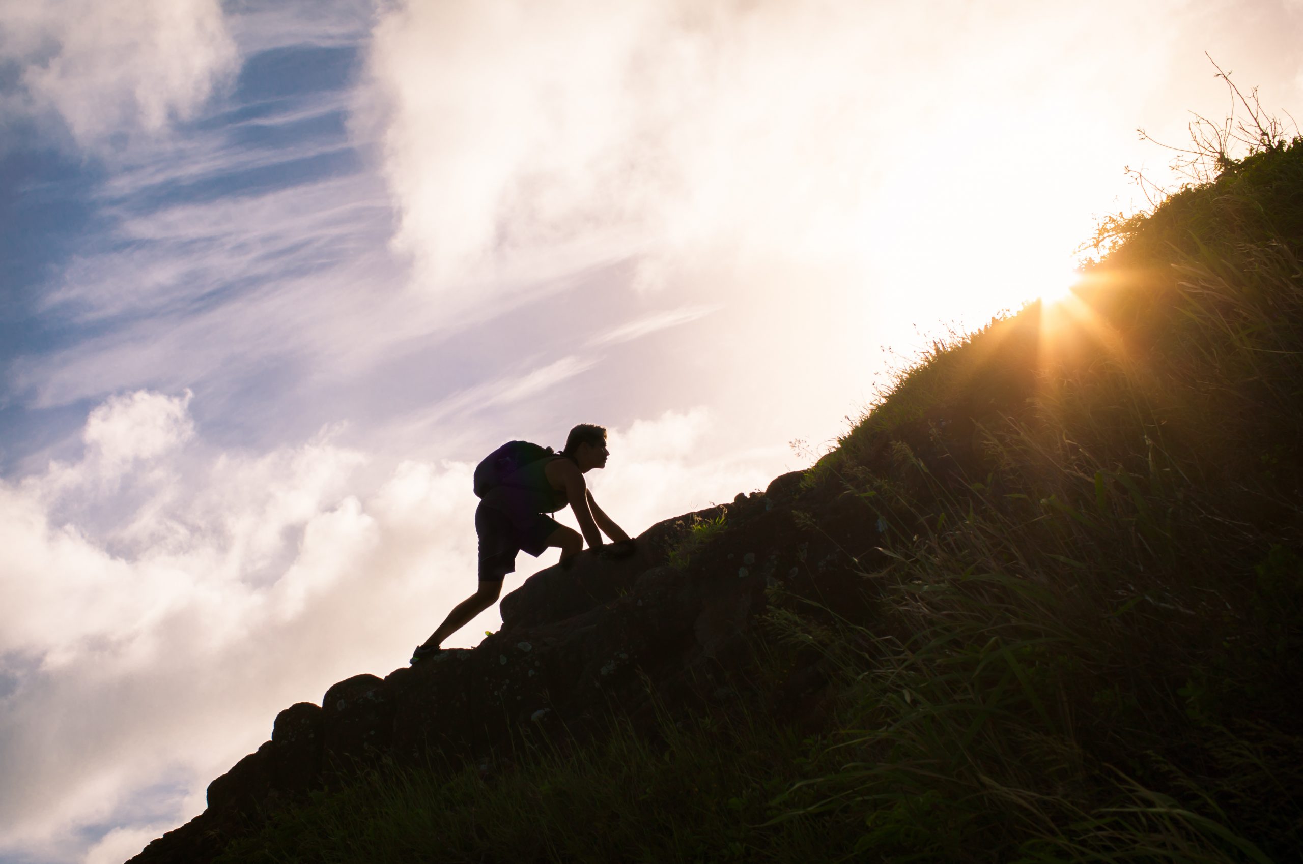 man climbing up mountain to reach top goal