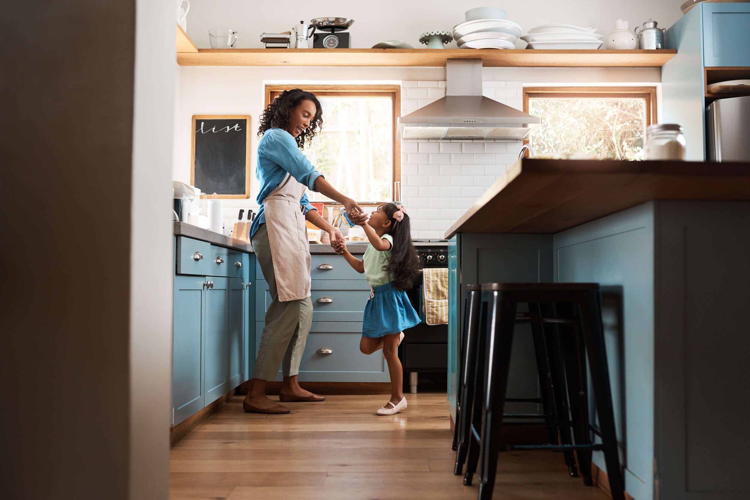 mother and daughter dancing in home kitchen
