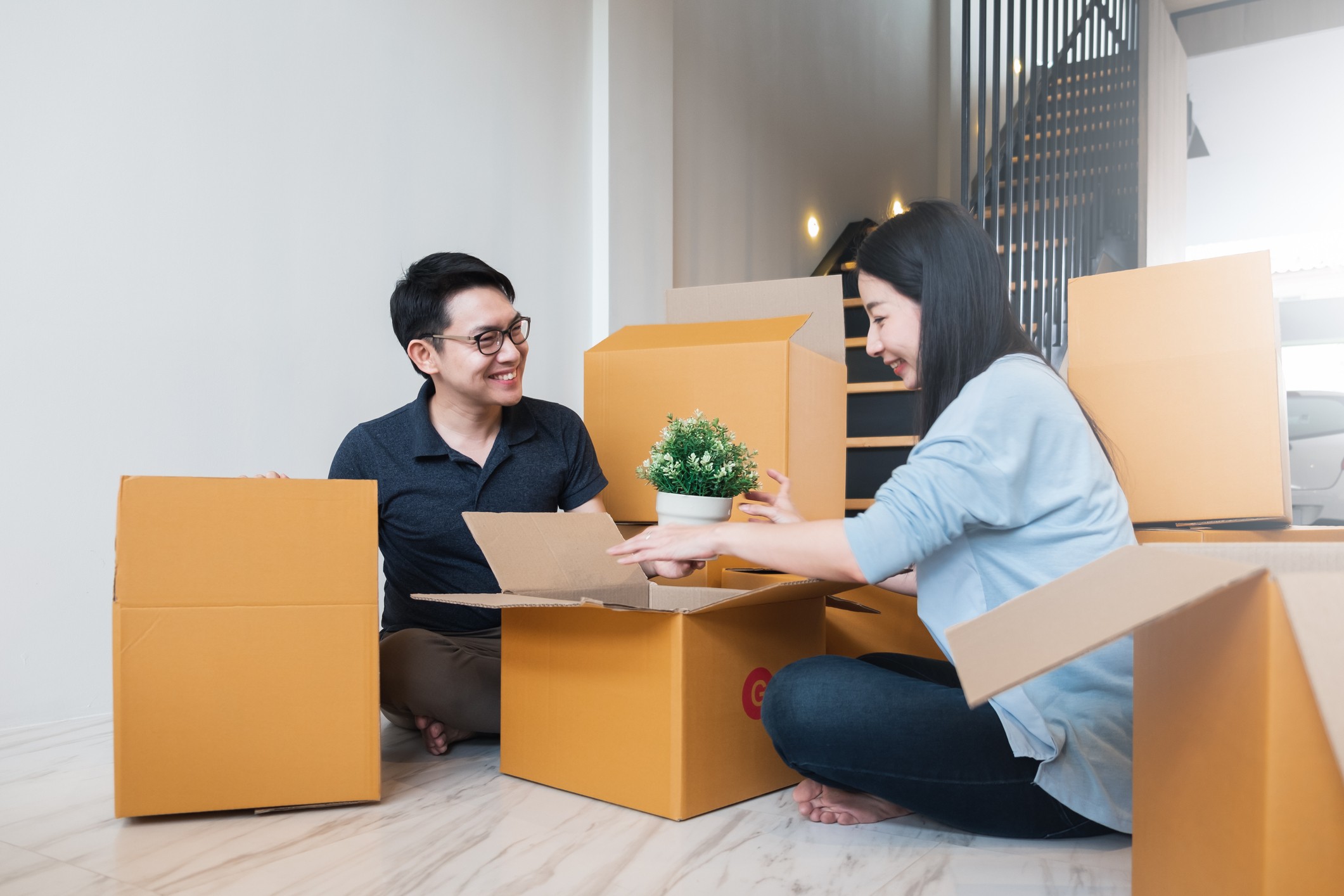 Asian couple moving to new home and unpacking boxes