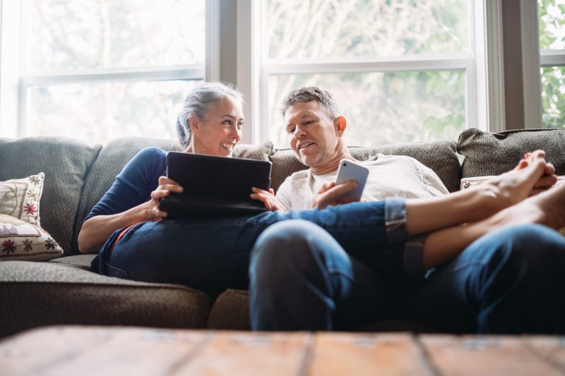 Mature Couple Relaxing with Tablet and Smartphone Looking at Investments
