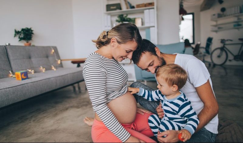 pregnant-couple-with-toddler-looking-at-moms-belly