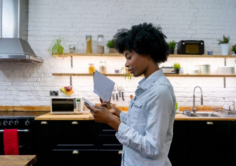 Portrait of a African American woman at home reading the mail - lifestyle concepts